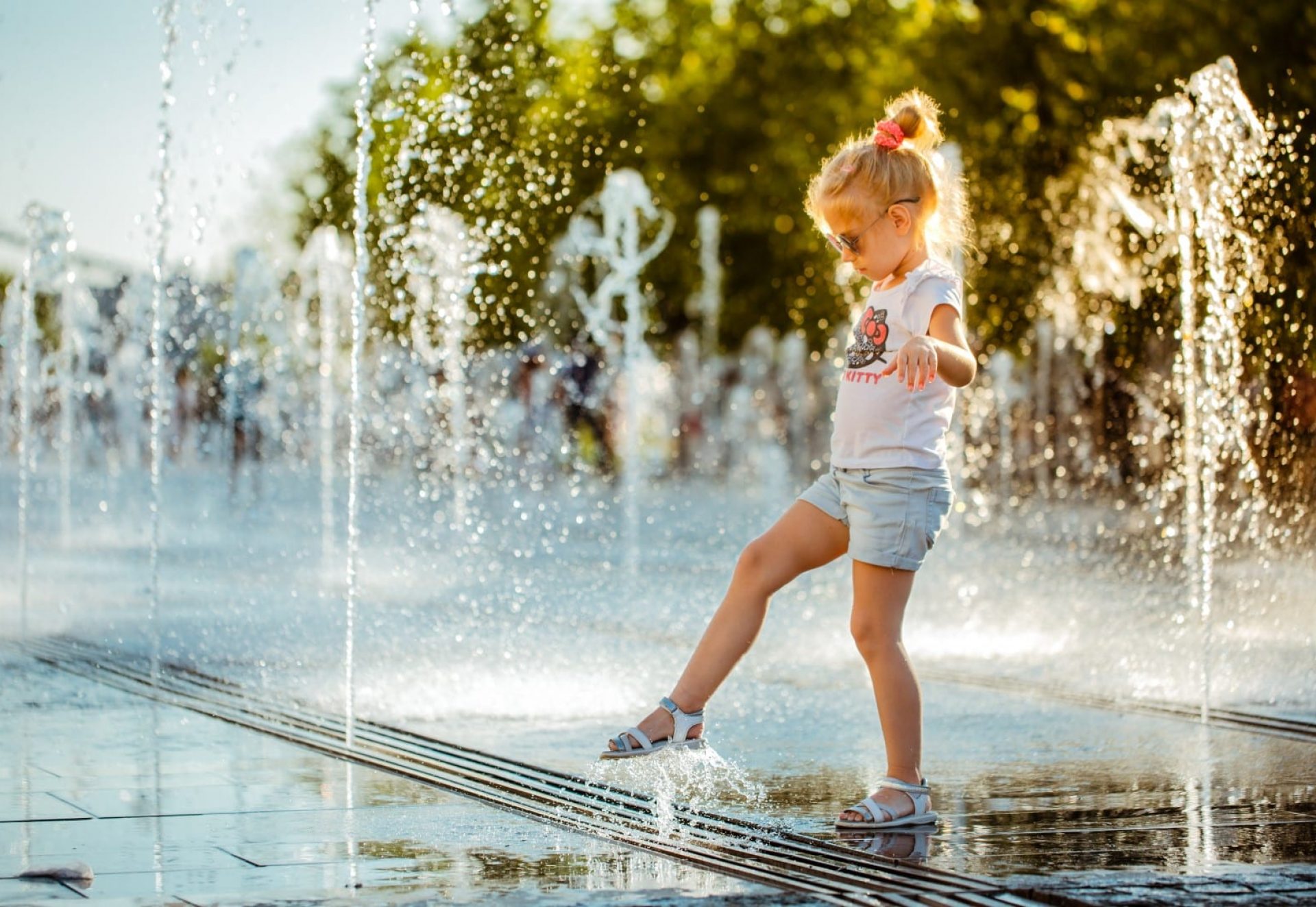 A little girl with her foot touches the water jet of a pedestrian fountain on the Crimean embankment in Muzeon Park.